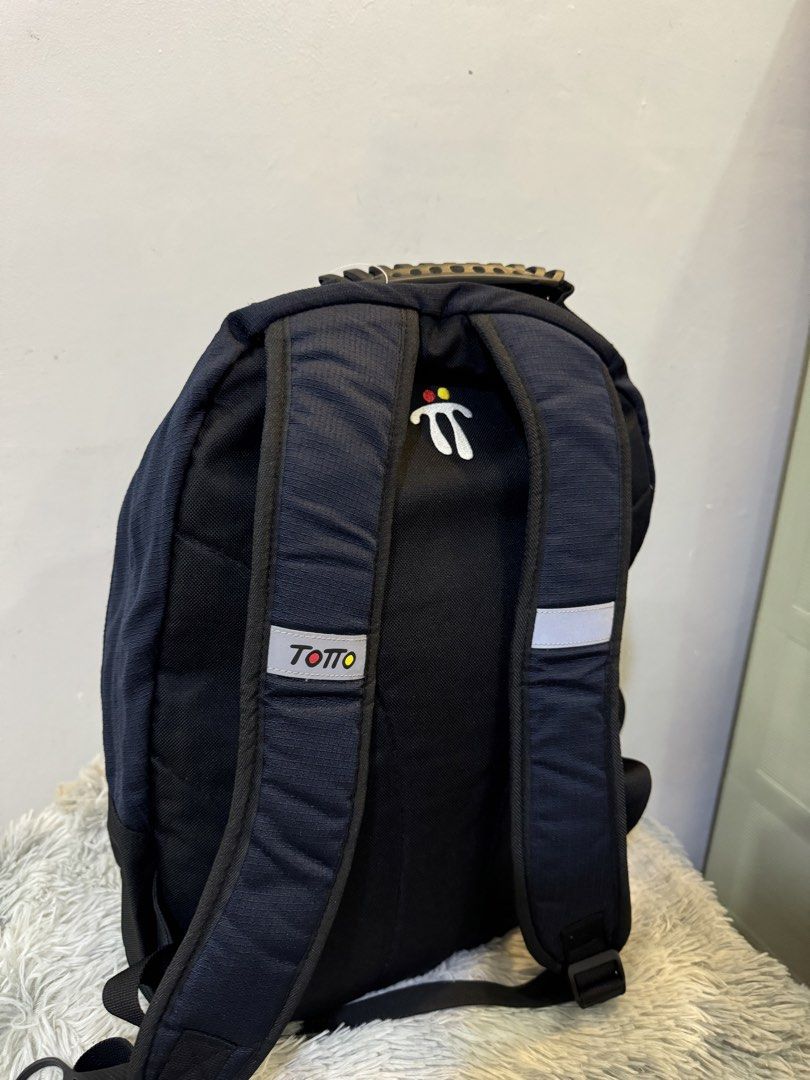 Totto Black Backpack with Durable Handle (Category: Backpacks) located in Urdaneta. Submitted by kathleenja24136 (Listing ID 1465958071, Image 3). Description: Totto black backpack with white logo embroidery on the front and back straps. Sturdy molded handle on top for easy carrying. Padded shoulder straps include reflective strips and logo branding. Multiple zip compartments and durable fabric construction. Great daily pack for school, work, or 