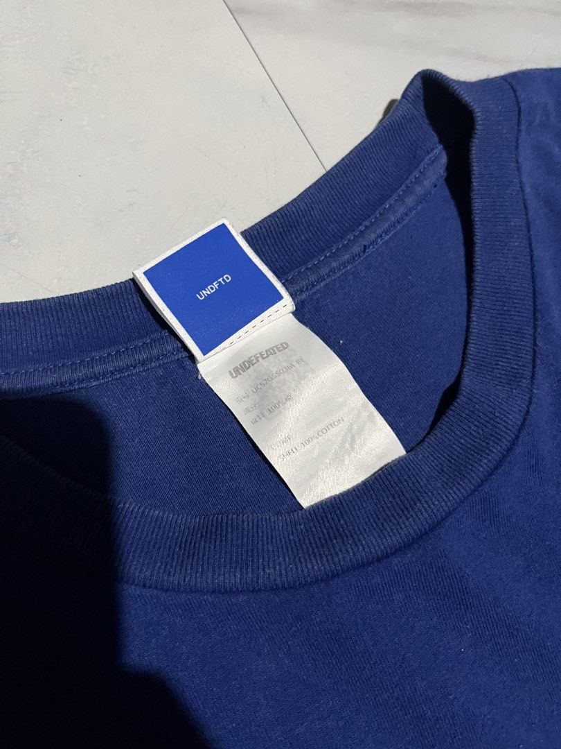 Undefeated Blue Script Logo T-Shirt Medium (Category: Tshirts & Polo Shirts ) located in Cavite. Submitted by christianzuuu (Listing ID 1466102905, Image 3). Description: - Brand: Undefeated - Style: Crewneck t-shirt in blue with classic script logo and 5 strikes icon - Size: Medium (tag attached) - Material: 100% cotton - Measurements: Roughly 27.5" x 22" - Condition: Clean, solid streetwear piece.