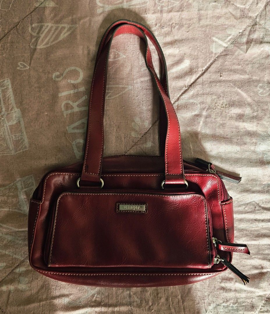Villager Red Leather Shoulder Bag with Multiple Compartments (Category: Shoulder Bags) located in Quezon City. Submitted by jackielicious17 (Listing ID 1466011088, Image 1). Description: - Brand: Villager - Color: Rich red with matching deep red fabric lining - Storage: Multiple interior and exterior zippered compartments - Exterior: Front slip pocket featuring a stylish metal logo plate - Straps: Sturdy double shoulder straps for comfortable dai