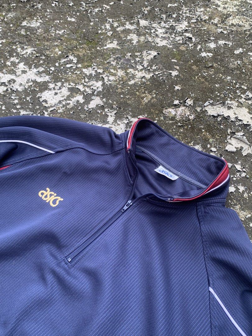 Vintage Asics Navy Blue Quarter Zip Track Jacket (Category: Coats, Jackets and Outerwear) located in Baguio. Submitted by jasthrift_ (Listing ID 1466040669, Image 2). Description: - Brand/Style: Navy blue Asics track jacket with quarter-zip collar - Design: Red and white contrast piping on shoulders, collar, and sides with an embroidered gold chest logo - Fit/Material: Ribbed cuffs, ribbed hem, and all-over textured fabric - Condition: Clean piec