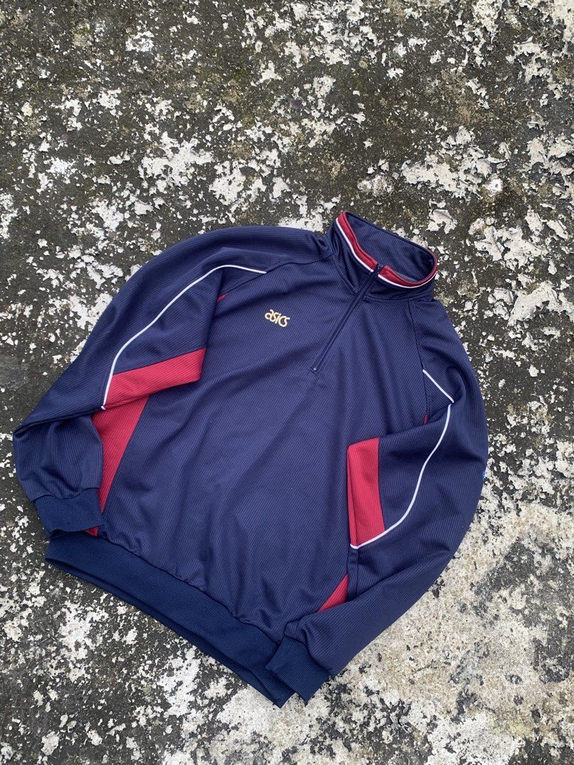 Vintage Asics Navy Blue Quarter Zip Track Jacket (Category: Coats, Jackets and Outerwear) located in Baguio. Submitted by jasthrift_ (Listing ID 1466040669, Image 1). Description: - Brand/Style: Navy blue Asics track jacket with quarter-zip collar - Design: Red and white contrast piping on shoulders, collar, and sides with an embroidered gold chest logo - Fit/Material: Ribbed cuffs, ribbed hem, and all-over textured fabric - Condition: Clean piec