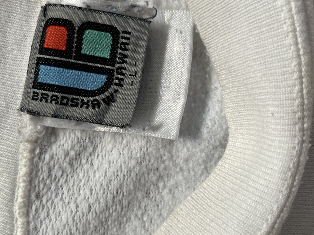 Vintage Bradshaw Hawaii Surf (Category: Coats, Jackets and Outerwear) located in Quezon City. Submitted by thriftshop_treasure (Listing ID 1466106055, Image 3). Description: vintage white crewneck sweatshirt featuring a surfboard and floral lei graphic on the back with “Bradshaw Hawaii Surf” 25x28.