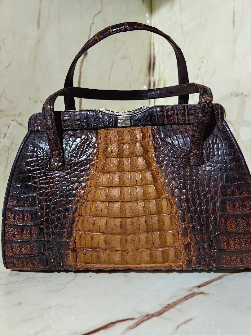 Vintage Brown Crocodile Leather Handbag (Category: Clutches) located in Tarlac. Submitted by jeremiah.curator.2026 (Listing ID 1466116551, Image 3). Description: - Material: Genuine crocodile leather with distinct hornback texture - Color: Rich brown gradient - Closure: Secure silver-tone metal top clasp - Carry: Dual top handles for hand or forearm wear - Design: Structured retro silhouette with a flat base for stability.