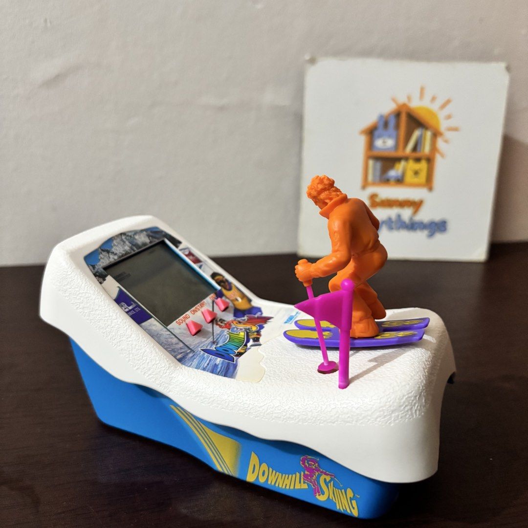VINTAGE Tiger Electronics Downhill Skiing handheld LCD game (Category: Interactive Toys) located in Taguig. Submitted by sunnyplaythingsph (Listing ID 1466086113, Image 1). Description: - Classic 80s tabletop electronic game featuring a Downhill Skiing theme - Includes a molded plastic skier figure mounted on a snowy white and blue console - Built-in LCD screen with responsive control buttons - Vibrant blue and yellow side graphics in clean condi