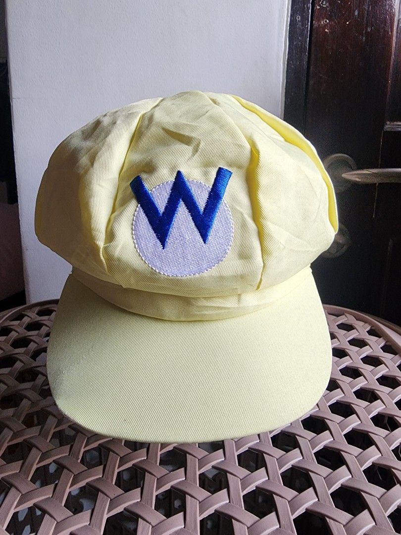Wario Yellow Cap With Blue W Logo (Category: Caps & Hats) located in Meycauayan. Submitted by MP_Shop (Listing ID 1465987695, Image 1). Description: - Color: Bright yellow with blue 'M' embroidered inside a white circle - Material: Comfortable cotton blend with inner lining - Fit: Adjustable back strap for a custom fit - Condition: Clean interior and exterior, ready to wear - Style: Classic solid brim baseball cap.