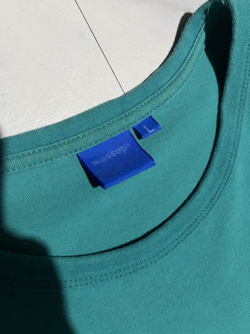 Wassup Teal T-Shirt Size L (Category: Tshirts & Polo Shirts ) located in Cavite. Submitted by christianzuuu (Listing ID 1466102790, Image 3). Description: - Brand: Wassup - Color: Teal green - Size: L (tag attached) - Design: Small left chest graphic with blue brand label, large white cursive print across the back - Details: Crew neck, short sleeves, small blue tag on bottom left hem - Condition: Brand new with tag.