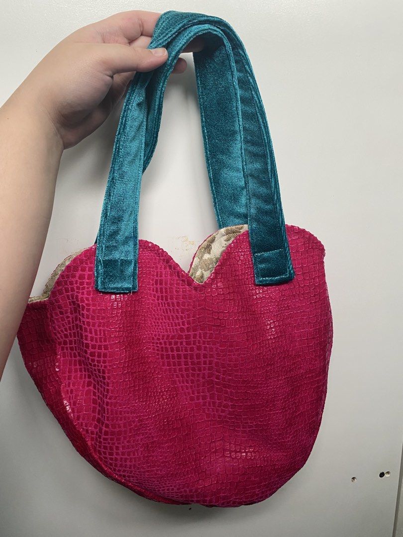 Where Sirius Dan Pink Heart Bag (Category: Shoulder Bags) located in Quezon City. Submitted by jeno_is_moving (Listing ID 1466000763, Image 3). Description: - Style: Bright pink faux snakeskin heart-shaped silhouette - Straps: Contrast teal blue velvet - Interior: Gold and white patterned fabric lining with an open pocket - Brand: Where Sirius Dan Nomadic Clothing Got it at Purveyr Fair! Used only once No flaws or any issues! Original price: P340