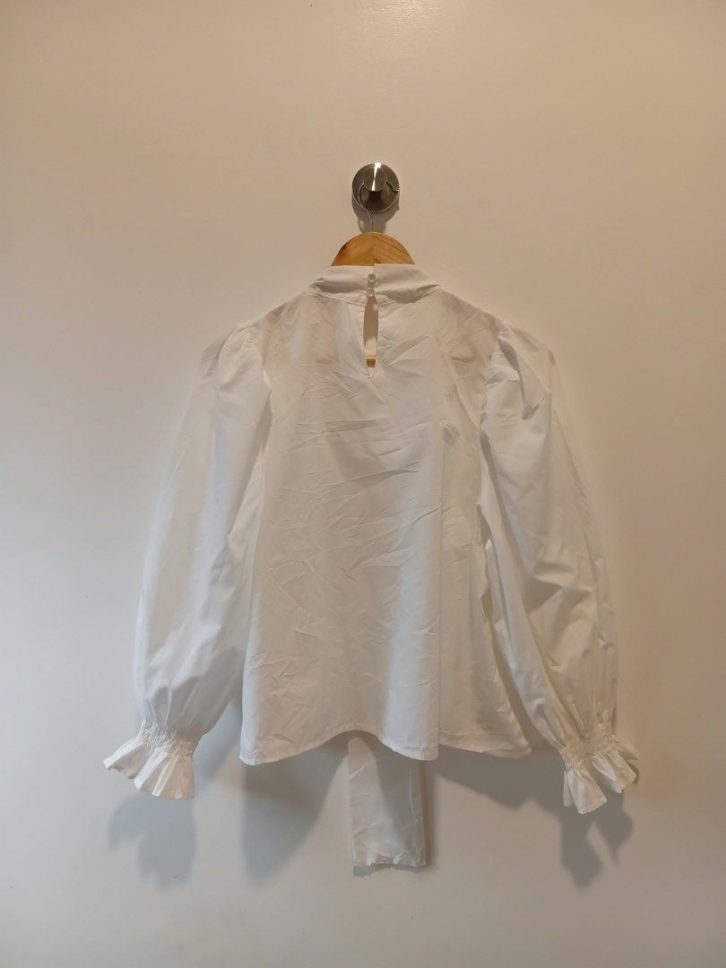 White Blouse with Ruffle Sleeves and Tie Neck (Category: Blouses) located in Antipolo. Submitted by wisecat.4a7eea (Listing ID 1466042248, Image 3). Description: - Color: White - Style: Long-sleeve blouse with trendy puff shoulders and ruffled cuffs - Details: High neckline with front tie string and back collar button closure - Fabric: Lightweight and comfortable - Fit: Best for small to medium frames - Versatility: Perfect for both workwear and 