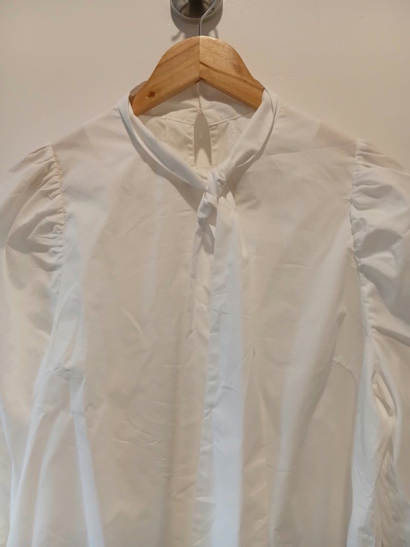 White Blouse with Ruffle Sleeves and Tie Neck (Category: Blouses) located in Antipolo. Submitted by wisecat.4a7eea (Listing ID 1466042248, Image 2). Description: - Color: White - Style: Long-sleeve blouse with trendy puff shoulders and ruffled cuffs - Details: High neckline with front tie string and back collar button closure - Fabric: Lightweight and comfortable - Fit: Best for small to medium frames - Versatility: Perfect for both workwear and 
