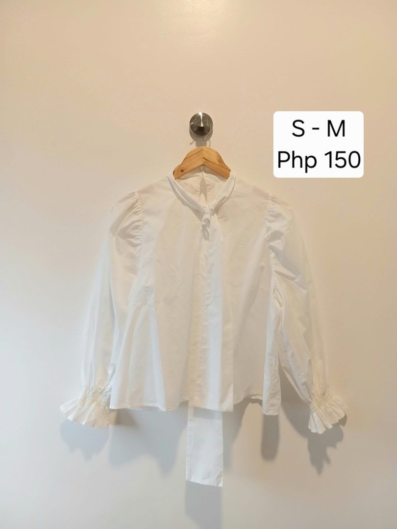 White Blouse with Ruffle Sleeves and Tie Neck (Category: Blouses) located in Antipolo. Submitted by wisecat.4a7eea (Listing ID 1466042248, Image 1). Description: - Color: White - Style: Long-sleeve blouse with trendy puff shoulders and ruffled cuffs - Details: High neckline with front tie string and back collar button closure - Fabric: Lightweight and comfortable - Fit: Best for small to medium frames - Versatility: Perfect for both workwear and 