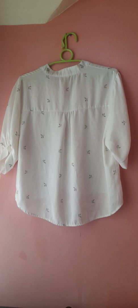 White blouse with small leaf pattern (Category: Blouses) located in Manila. Submitted by sec0ndbloom (Listing ID 1466003337, Image 2). Description: - Design: White button-down blouse with an elegant grey leaf print - Neckline & Sleeves: V-neck collar and long sleeves with slightly cuffed ends - Fit & Cut: Light, breezy material with a flattering curved hemline (longer in the back) - Versatility: Perfect for work or casual weekends; easy to match 