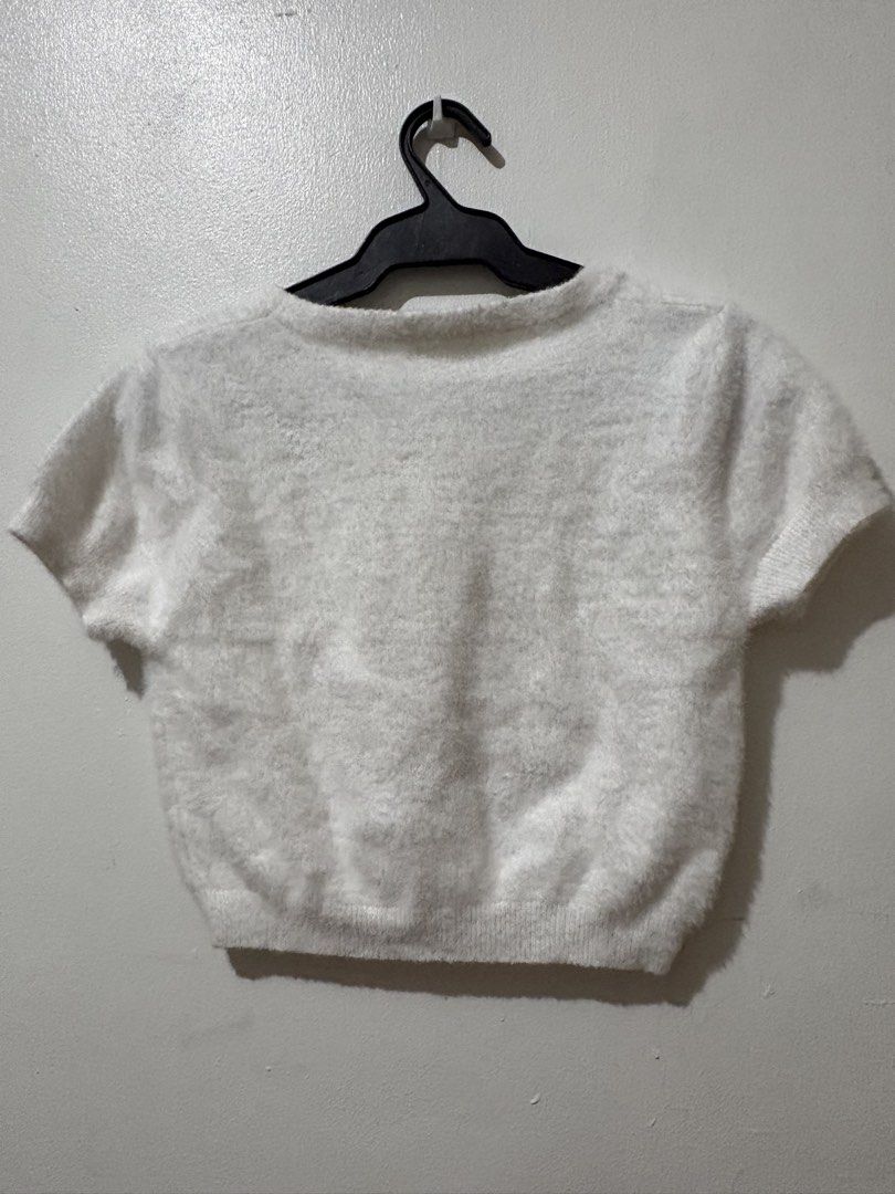 White fluffy knit short sleeve crop top (Category: Shirts) located in Manila. Submitted by nykji96 (Listing ID 1465964811, Image 2). Description: - Color: Solid white - Style: Short sleeve crop top with a boxy cut and scoop neckline - Texture: Soft and fuzzy all over with a ribbed bottom hem - Material: Lightweight and stretchy for a comfortable fit.