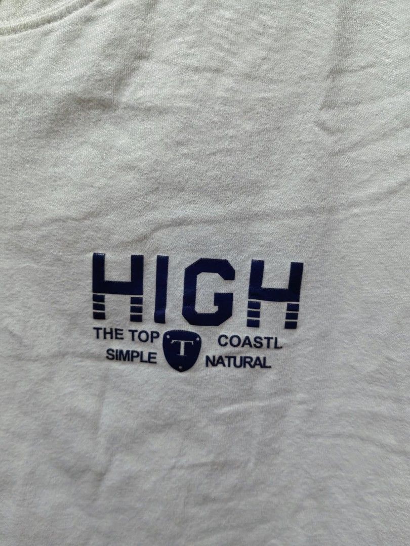 White HIGH Graphic T-Shirt (Category: Shirts) located in Quezon City. Submitted by jasalexiz (Listing ID 1466107612, Image 2). Description: - Color: White - Material: Soft, comfortable cotton - Design: Small dark blue graphic print on chest with shield logo - Cut: Crew neck, short sleeves, relaxed casual fit - Condition: Brand new with standard collar tag - Perfect for daily casual wear.