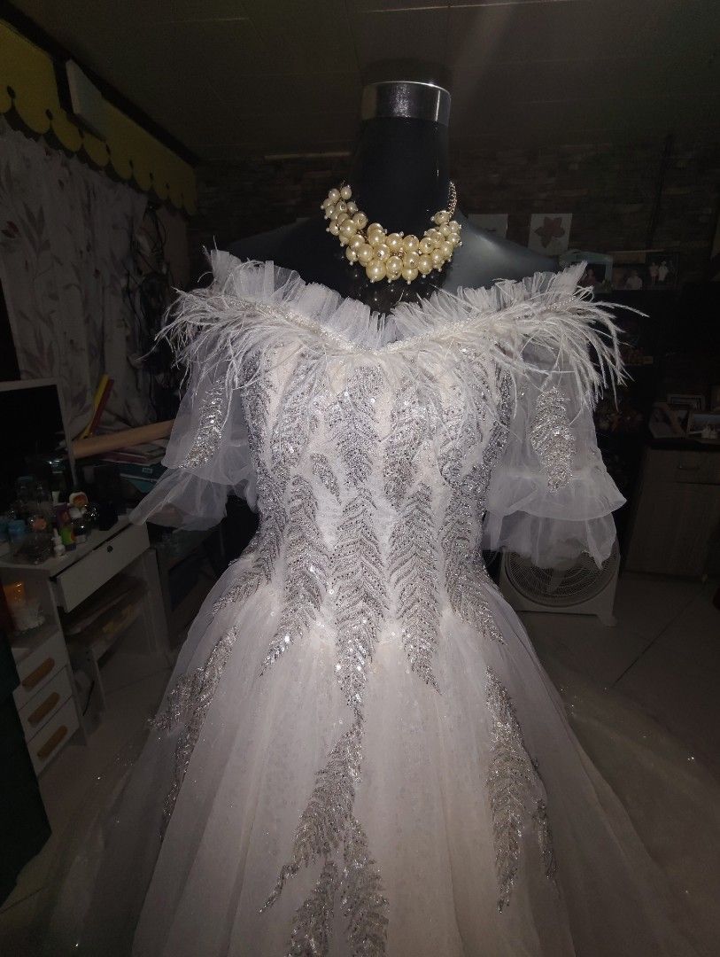 White Off-Shoulder Wedding Gown with Sequins and Long Train (Category: Evening dresses & gowns) located in Manila. Submitted by duffy-080 (Listing ID 1466047739, Image 2). Description: - Color: White - Style: Off-shoulder gown with corset back and long train - Details: All-over sparkles and sequins, feather trim on neckline and sleeves - Embroidery: Silver leaf patterns cascading down the front and train - Freebie: Pearl statement necklace includ