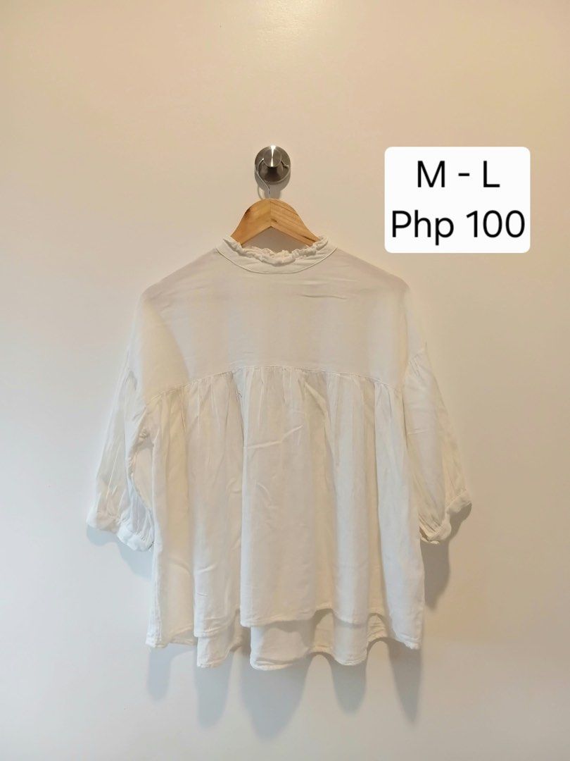 White ruffle neck tie back blouse M-L (Category: Blouses) located in Antipolo. Submitted by wisecat.4a7eea (Listing ID 1466040489, Image 1). Description: - Color: White - Size: Fits Medium to Large - Design: High ruffled neckline with single back button - Details: Cute back cutout with three ribbon ties and gathered front/back yoke - Sleeves: Mid-length with cuffs - Fabric: Lightweight and comfortable.