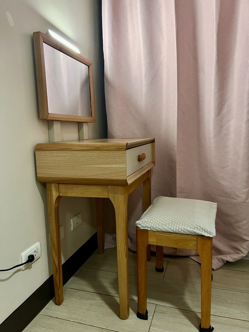 Wooden Vanity Table With Mirror And Matching Stool (Category: Tables & Sets) located in Makati City. Submitted by rilachan6666 (Listing ID 1466081402, Image 3). Description: - Set includes: Wooden vanity table and matching stool - Design: Light wood frame with a clean white drawer and wooden pull handle - Mirror: Attached rectangular mirror on sturdy supports - Seating: Stool features a comfortable white textured patterned cushion - Size: Compact