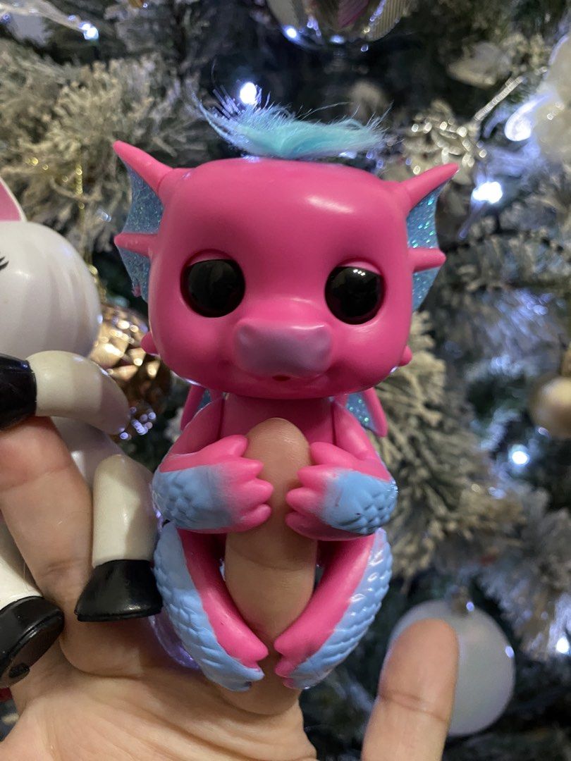 WowWee Fingerlings Baby Dragon Sandy (Category: Kids Toys) located in Las Pinas. Submitted by sherylandmargaux (Listing ID 1466126090, Image 1). Description: Baby Dragon Sandy, an interactive toy featuring a hot pink body with blue glittery wings, claws, and a matching tuft of hair. This collectible electronic pet responds to touch, motion, and sound with blinking eyes, head turns, and cute dragon noises..