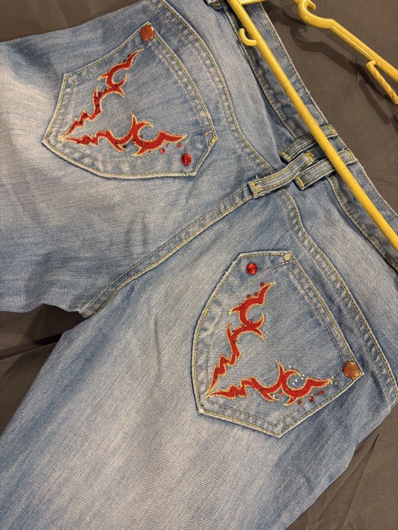 Y2k Low waisted Flare Pants (Category: Jeans) located in Quezon City. Submitted by hannahhhhssclosetttt (Listing ID 1466028890, Image 3). Description: - Back Details: Embroidered red flame/tribal designs with matching rhinestones - Vibe: Fun Y2K statement piece - waist 27/28 inches -length 35.5 inches .