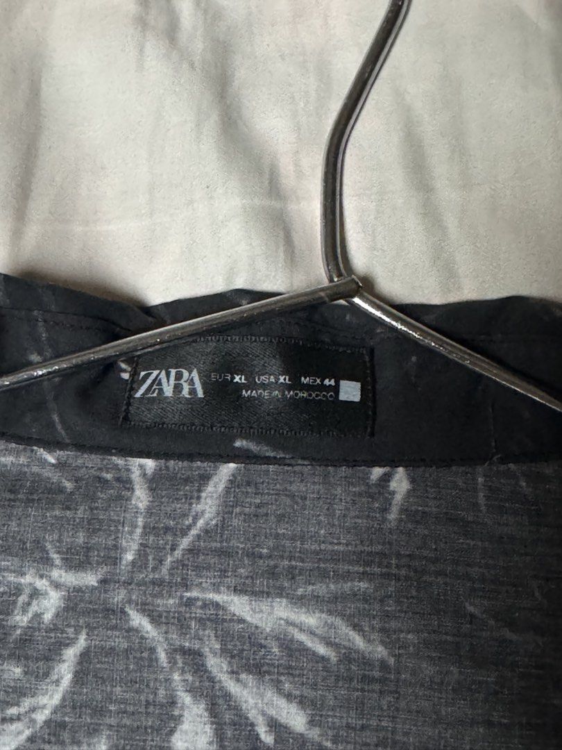 Zara Black Graphic Print Button Down Shirt XL (Category: Tshirts & Polo Shirts ) located in Manila. Submitted by seangoart (Listing ID 1466072753, Image 2). Description: - Brand: Zara - Size: XL - Color/Pattern: Black with white sketched palm trees and abstract lines - Style: Open camp collar, button-down, relaxed fit - Origin: Made in Morocco - Material: Lightweight fabric - Condition: Great pre-loved condition with no noticeable flaws.