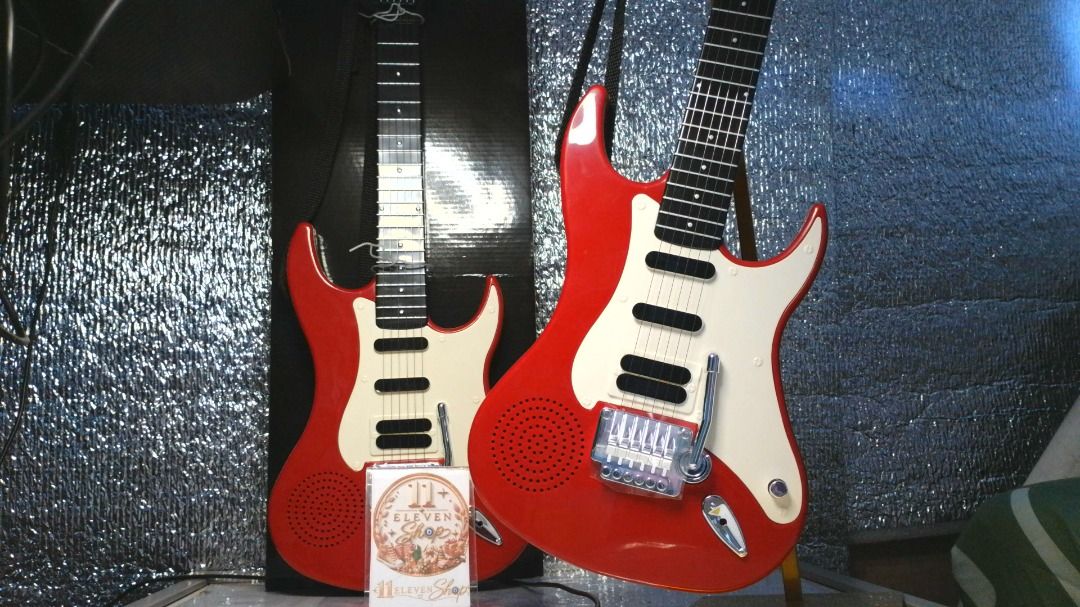 6 String Electric Guitar with Built-in Speaker and Box (Category: Musical Instruments) located in Binan City. Submitted by 11eleven.shop (Listing ID 1466243980, Image 3). Description: - Bright red electric guitar toy for kids - 2 Available - Features a white pickguard, black pickup details, and chrome bridge with whammy bar - Built-in speaker on the body for instant jamming - Includes original retail box with Japanese text.