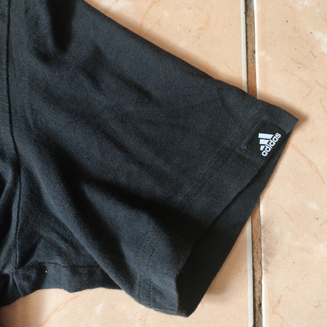 Adidas Black Graphic T-Shirt Size M (Category: Tshirts & Polo Shirts ) located in Pili. Submitted by emmanuelmotos (Listing ID 1466176196, Image 2). Description: - Brand: Adidas - Color: Black with large white distressed brushstroke logo - Size: Medium (Standard fit) - Material: 100% Cotton - Details: Crew neck, short sleeves, small Adidas logo tag on left sleeve - Production Date: 09/20 - Condition: Excellent, great for casual streetwear.