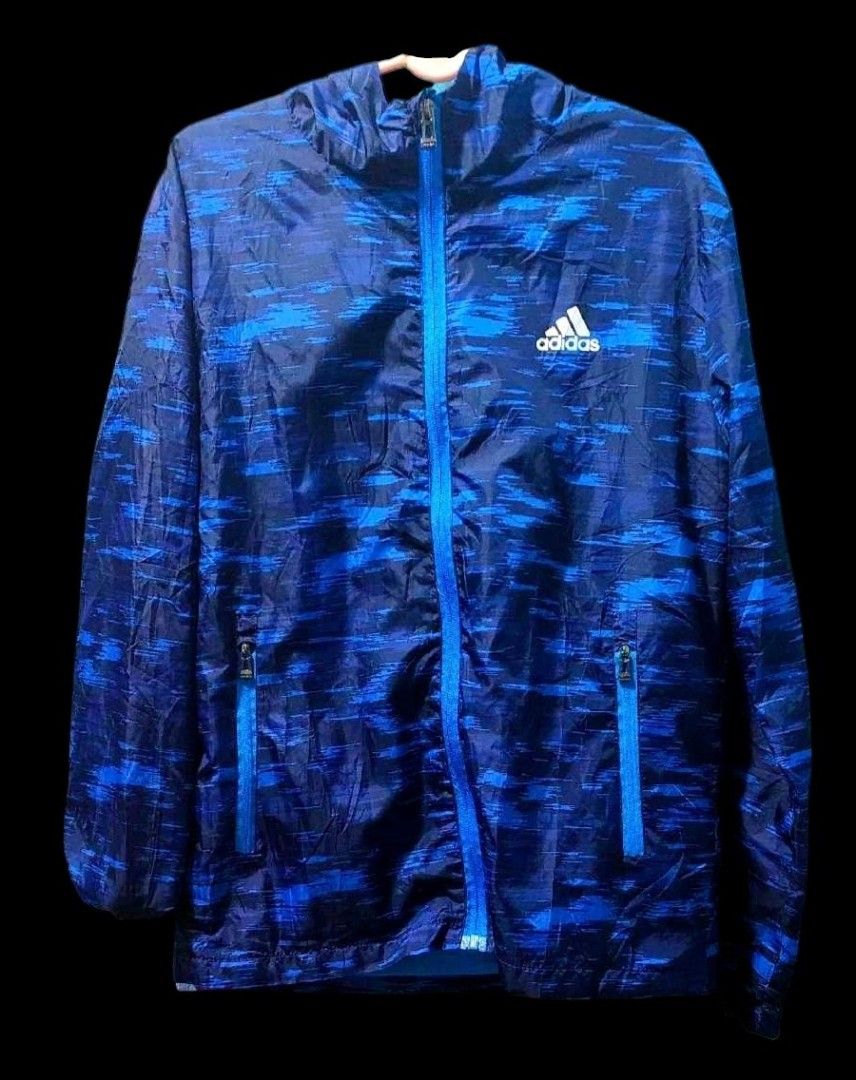 Adidas Blue Windbreaker Jacket (Category: Coats, Jackets and Outerwear) located in Camiling. Submitted by sundot_kalikot (Listing ID 1466326605, Image 1). Description: - Brand: Adidas - Design: Stylish blue camo-print with striking bright blue zippers - Features: Full zip front, attached hood, and two secure zippered side pockets - Material: Lightweight and breathable, ideal for running or layering on breezy days - Branding: Classic white Adidas 