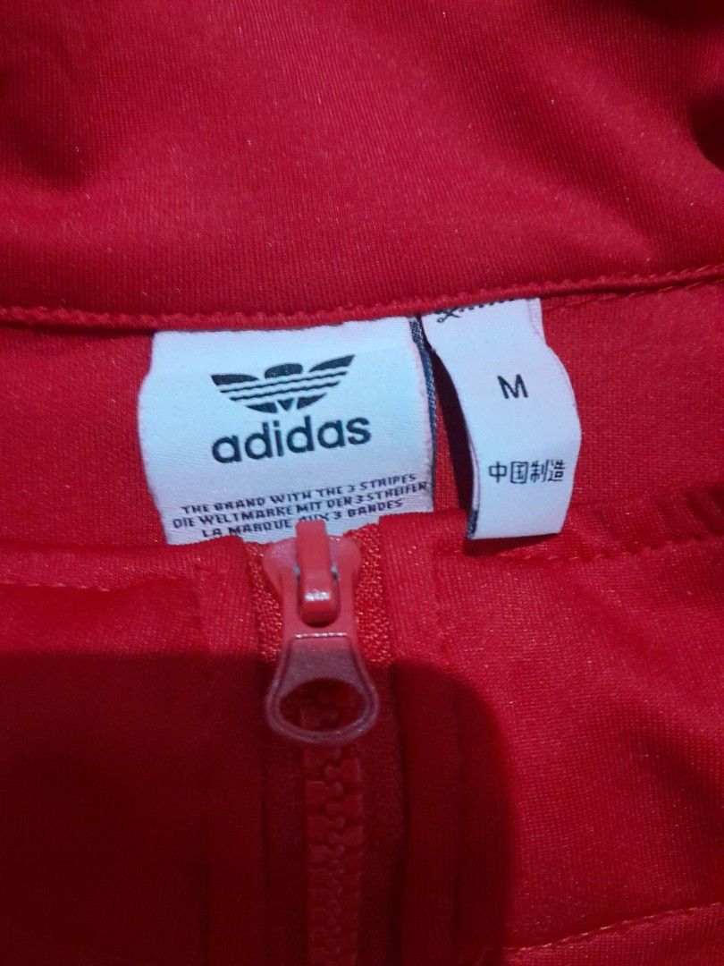 Adidas Red Track Jacket Size M (Category: Coats, Jackets and Outerwear) located in Calamba. Submitted by ysabellascloset17 (Listing ID 1466291687, Image 3). Description: - Brand: Adidas - Color: Bright red with white stripes - Logo: Iconic Trefoil logo on the chest - Design: Full zip front, stand-up collar, ribbed cuffs and hem - Size: Medium (M) 25 x 26.5 - Condition: Clean stitching inside and out - Style: Comfortable everyday sporty layer.