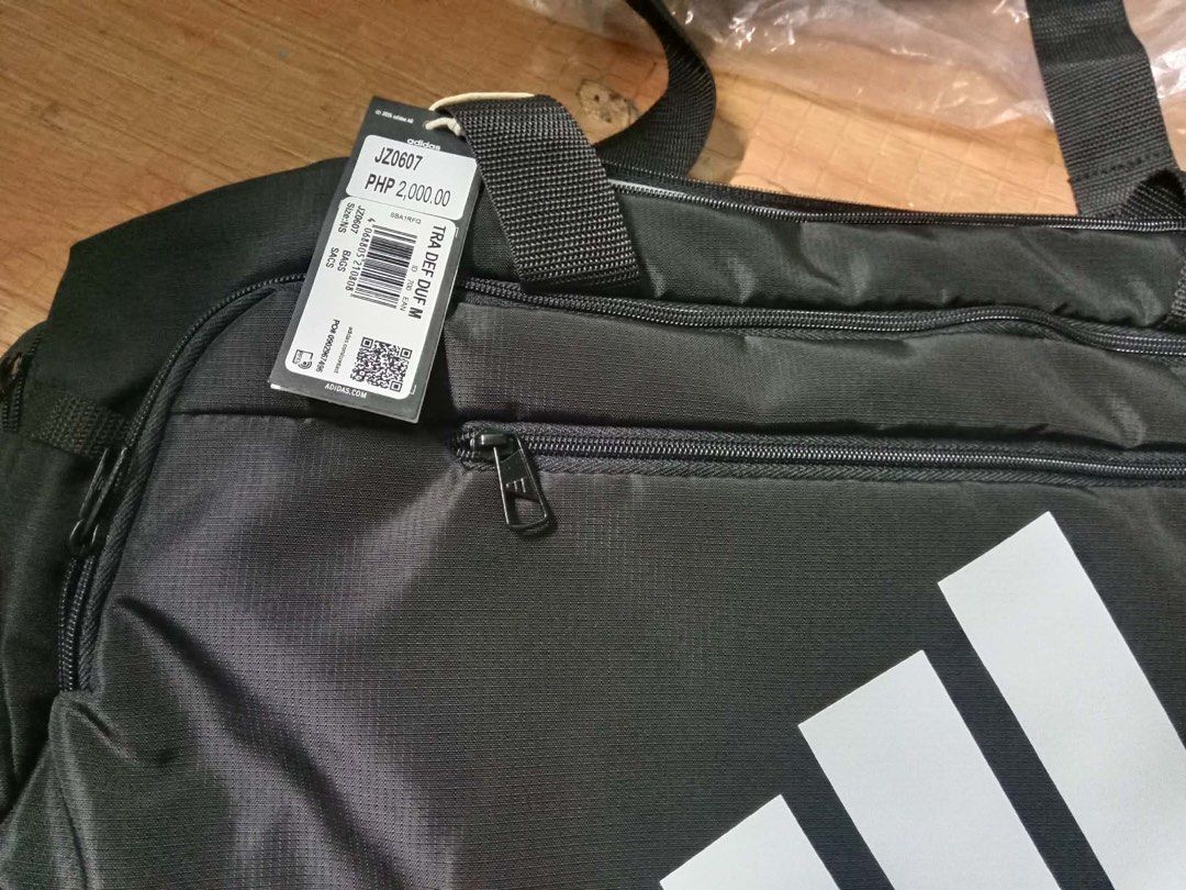 Adidas Training Defense Duffel Bag Medium Black (Category: Sling Bags) located in Manila. Submitted by whenn_1985 (Listing ID 1466288309, Image 3). Description: - Brand new with retail tag (2,000 PHP value) still in original plastic packaging - Color: Classic black with white Adidas logo on the front - Size: Medium, perfect for gym and training gear - Storage: Multiple zippered compartments to keep your items organized - Comfort & Durability: Stu