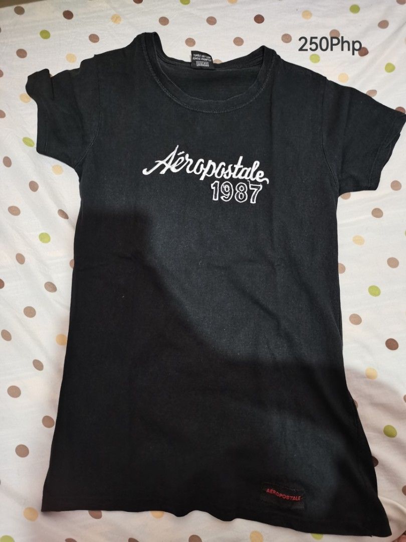 Aeropostale 1987 Black T-shirt Medium (Category: Tshirts & Polo Shirts ) located in Dipolog. Submitted by true.brclo_thing (Listing ID 1466264152, Image 1). Description: - Brand: Aeropostale - Color: Black - Size: Medium - Design: White cursive logo text with '1987' print on chest and red tag near bottom hem - Fit/Style: Short sleeves, crew neck, comfortable everyday cotton material .