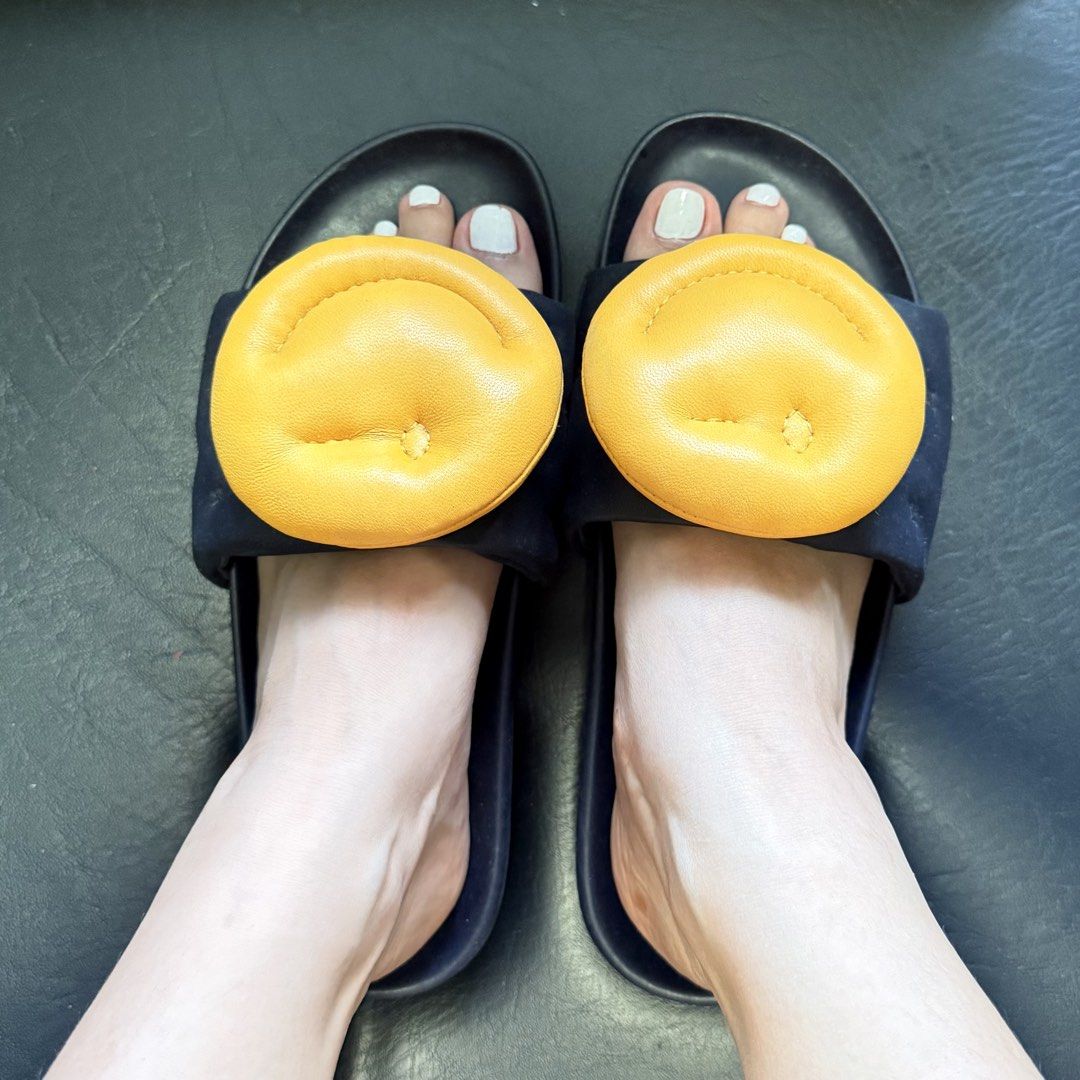 Anya Hindmarch Smiley Leather Slides (Category: Flats & Sandals) located in Manila. Submitted by she_alice (Listing ID 1466327306, Image 3). Description: - Brand: Anya Hindmarch - Material: Premium black leather with slip-on design - Feature: Large yellow puff smiley face on the strap - Comfort: Molded footbeds for all-day wear - Inclusion: Original box included -Bought for almost 15k .