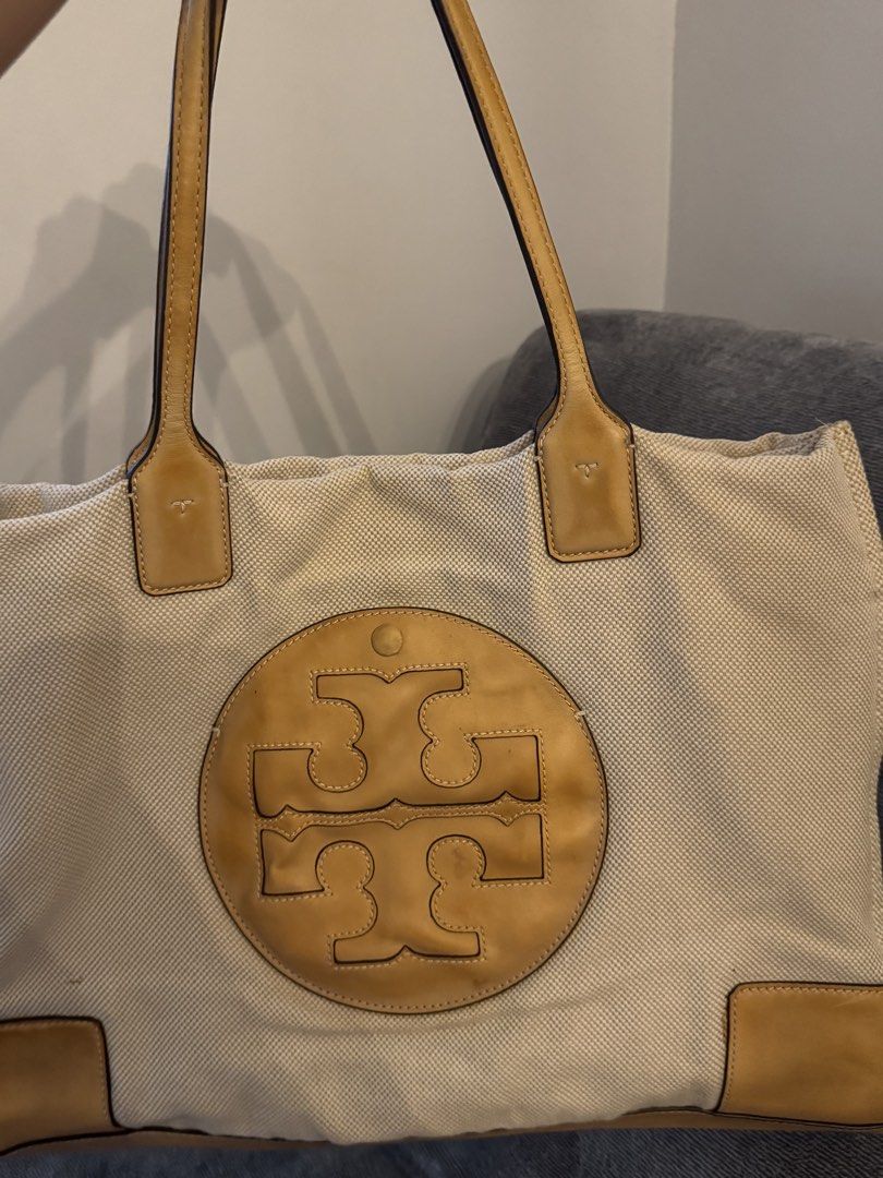 Auth Tory Burch Tote Bag (Category: Tote Bags) located in Pasay City. Submitted by shop.stylestaple (Listing ID 1466212173, Image 2). Description: - Tory Burch Canvas Tote Bag Tan Cream - Brand: Tory Burch - Style: Canvas and leather tote bag - Color: Cream canvas with tan leather trim and handles - Design: Large cut-out double T logo on the front, structured leather base - Condition: Pre-loved with noticeable canvas discoloration and staining (m
