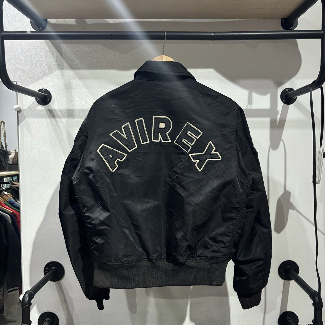 Avirex Black Flight Bomber Jacket with Patches (Category: Coats, Jackets and Outerwear) located in Bambang. Submitted by heats777 (Listing ID 1466224825, Image 3). Description: - Authentic black Avirex flight jacket - Multiple military-style patches on the front and sleeves - Bold AVIREX lettering embroidered across the back shoulders - Heavy-duty branded zipper pull - Comfortable ribbed cuffs and hem - Classic pilot silhouette with collar - Clea