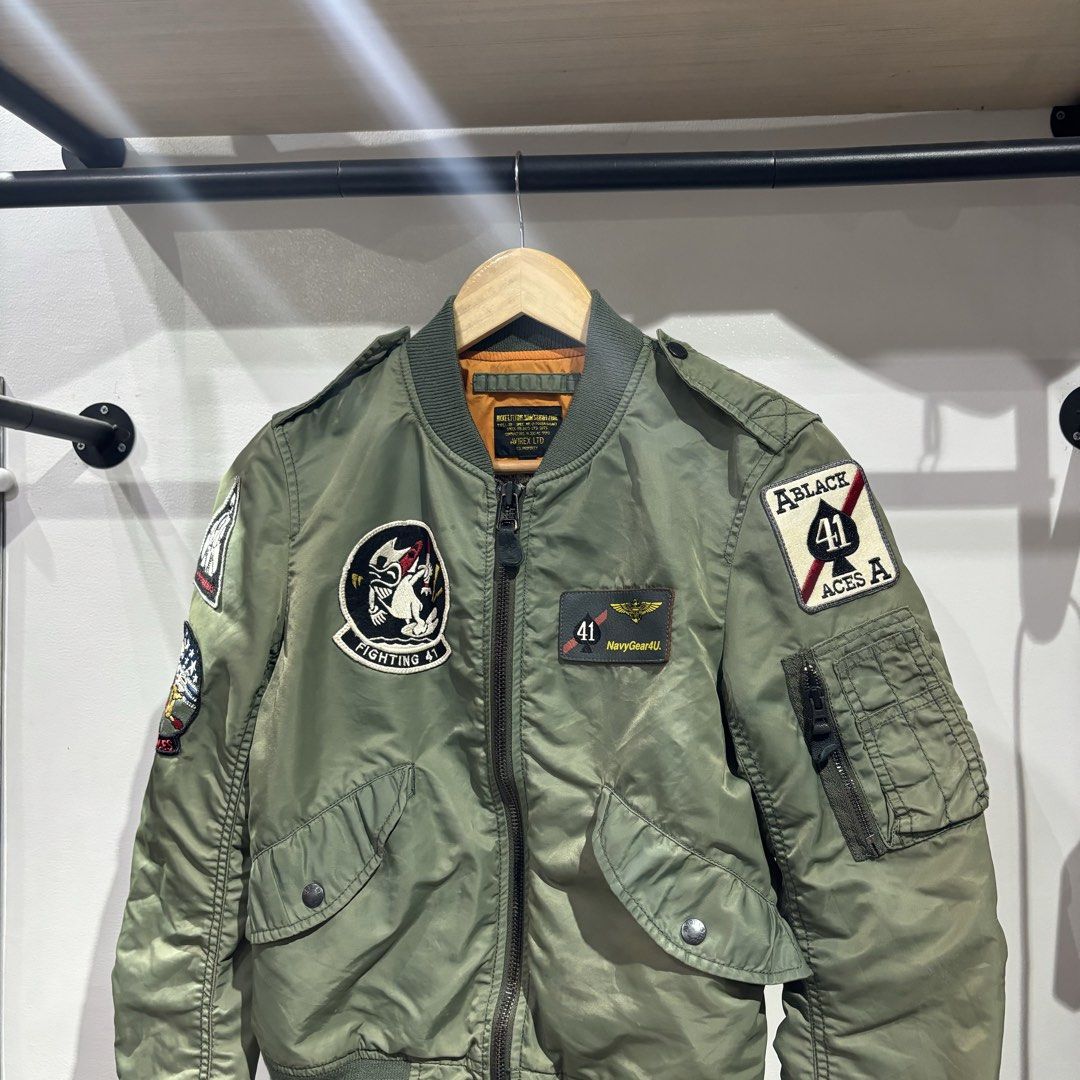Avirex Flight Bomber Patch Jacket (Category: Coats, Jackets and Outerwear) located in Bambang. Submitted by heats777 (Listing ID 1466225038, Image 1). Description: - Color: Trendy sage green with vibrant orange inner lining - Design: Military-style embroidered patches featuring the VF-41 Black Aces on the sleeve and back - Storage: Utility zipper pocket on the left arm and two slanted snap-button front pockets - Comfort: Classic ribbed collar, cu
