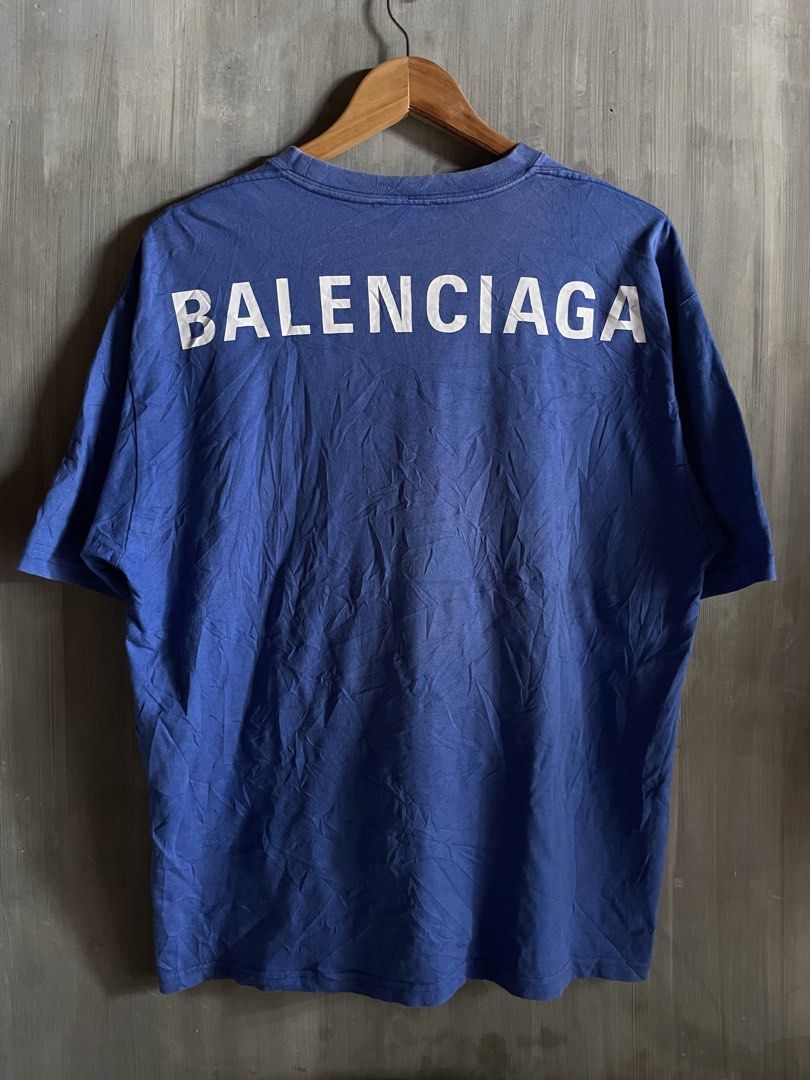 Balenciaga Back Logo Tee Blue Size S (Category: Luxury Apparel) located in M'Lang. Submitted by thrift_finds2 (Listing ID 1466176919, Image 3). Description: - Brand: Balenciaga - Color: Blue with large white lettering on back shoulders - Size: S (Relaxed fit) - Design: Classic crew neck, short sleeves, black inner collar label - Origin: Made in Portugal - Style: Ultimate streetwear staple.