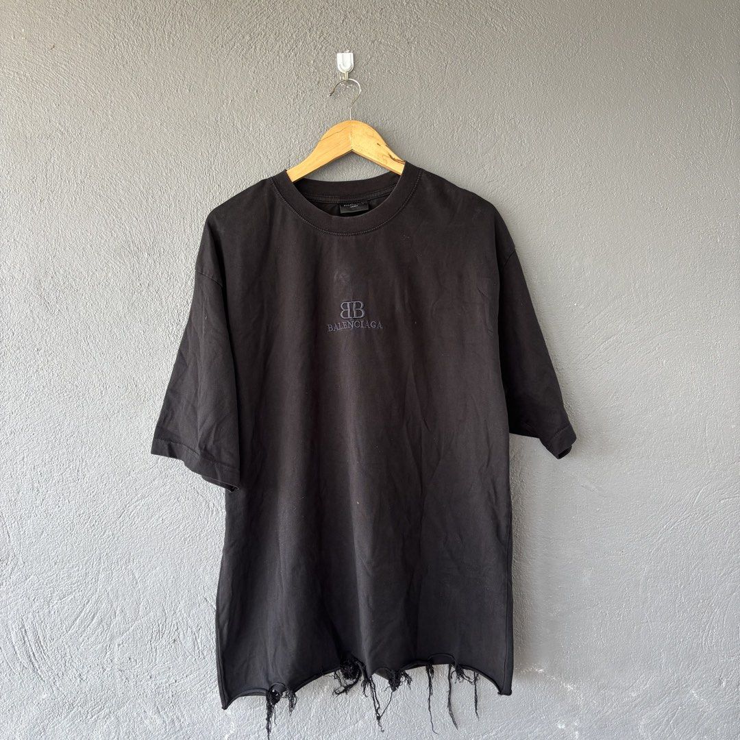 Balenciaga distressed tee (Category: Tshirts & Polo Shirts ) located in San Fernando. Submitted by diff.thr1ft (Listing ID 1466170454, Image 1). Description: - Brand: Balenciaga - Color: Black - Size: L (Unisex) - Material: High-quality cotton - Design: Distressed raw-edge hem with hanging threads, embroidered BB logo on the chest - Origin: Made in Portugal - Condition: Excellent pre-owned condition with intentional factory distressing.