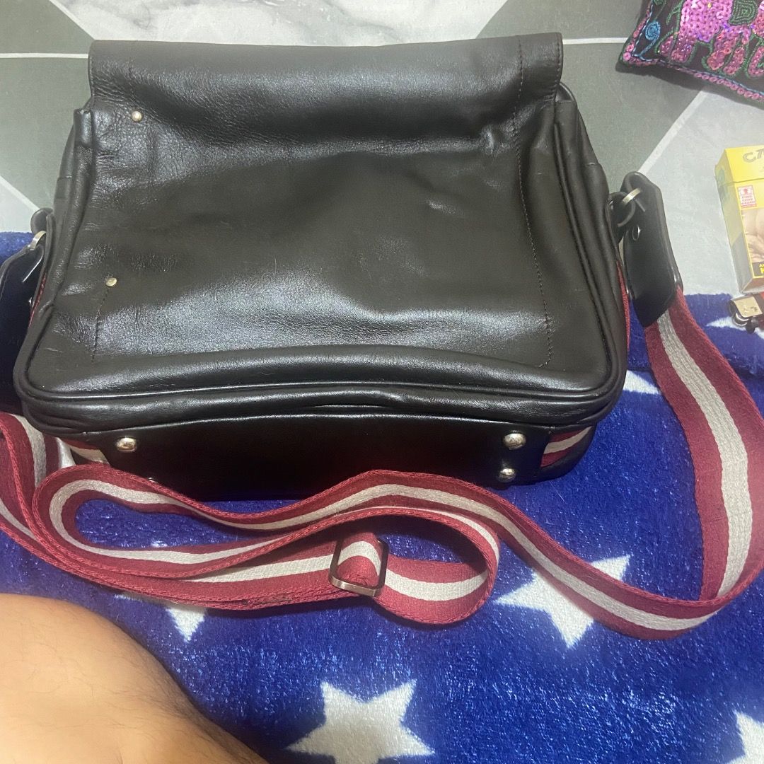 Bally Black Leather Messenger Bag with Red Stripe Strap (Category: Sling Bags) located in Paranaque City. Submitted by vincechong0813 (Listing ID 1466171541, Image 2). Description: - Brand: Bally - Color & Material: Classic black, genuine leather - Design: Structured flap top with secure zip closure underneath - Strap: Adjustable canvas strap featuring the iconic red and white Bally stripe - Hardware: Silver-tone accents with branded zipper pull 