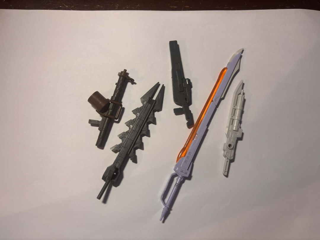 bandai gundam scraps #17 (Category: Action & Battle Toys) located in Taguig. Submitted by livehorse.8cf1df (Listing ID 1466191196, Image 1). Description: - Variety of plastic action figure weapons and accessories - Includes large orange-bladed sword, grey spiked blade, dark rifle, brown rifle with strapped gear, and white blaster - Pulled from old display parts boxes - Ideal for custom kitbashing or replacing lost gear - Selling as one complete s