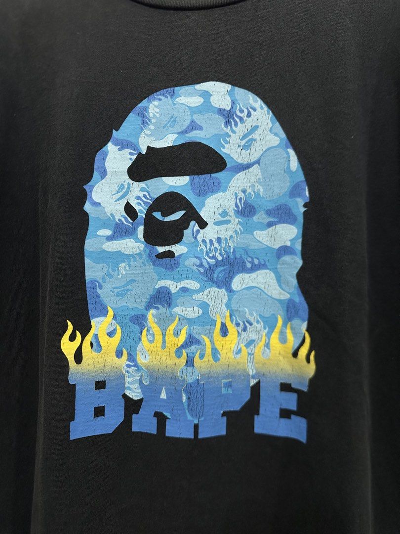 BAPE Ape Head Flame Tee Black Blue XL (Authentic) (Category: Tshirts & Polo Shirts ) located in Manila. Submitted by ylsrarities (Listing ID 1466332027, Image 2). Description: Pre owned with normal signs of wear and age. The black body shows light natural fading and fabric wear. The graphic has some natural print texture and light signs of aging from use. No major holes or tears noted. • Brand: A Bathing Ape / BAPE • Model: Ape Head Flame Tee • D