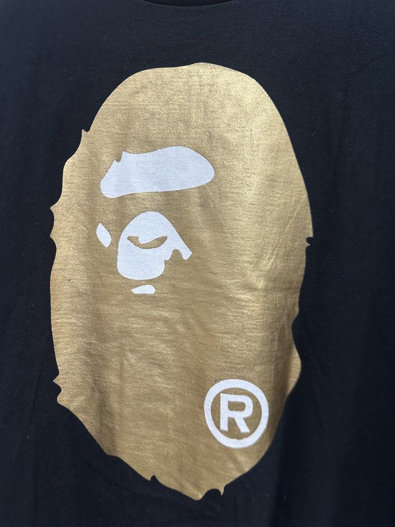 BAPE Big Ape Head Gold Mirror Tee Black L (Authentic) (Category: Tshirts & Polo Shirts ) located in Manila. Submitted by ylsrarities (Listing ID 1466332949, Image 2). Description: Pre owned with normal signs of age and wear. The metallic gold graphics show natural surface texture and signs of aging consistent with wear. Black body remains in good overall condition with no major holes or tears noted. • Metallic gold Big Ape Head front graphic • La