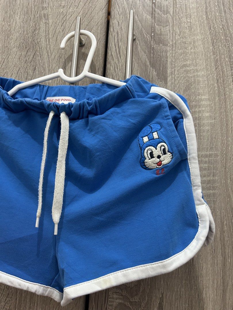 Bebe De Pino Blue Shorts with Jollibee Patch (Category: Babies & Kids Fashion) located in Makati City. Submitted by michellecollado07 (Listing ID 1466313326, Image 2). Description: Bright blue toddler shorts from Bebe De Pino. Elastic waistband with adjustable white drawstring. White piping trim along the sides and hem. Cute blue bunny character patch on the front pocket plus a red 'B' patch. Signature Bebe De Pino logo patch stitched on the back