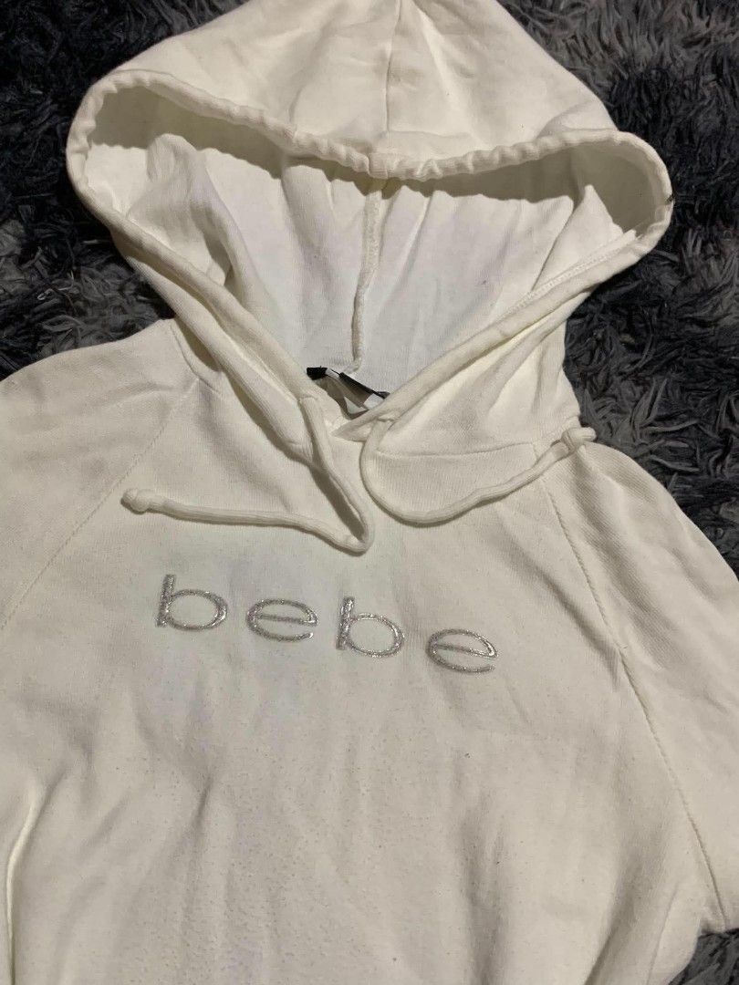 bebe White Hoodie Sweatshirt (Category: Coats, Jackets and Outerwear) located in Manila. Submitted by vinnrys (Listing ID 1466265273, Image 3). Description: - Brand: Bebe - Color: White with silver glitter chest lettering - Origin: Made in USA - Fit: Classic fitted style, great for layering - Features: Adjustable drawstring hood and long sleeves - Condition: Excellent basic piece for casual wear.