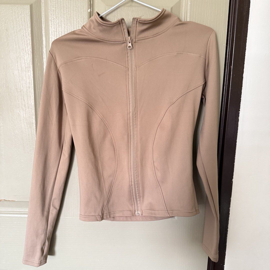 Beige Activewear Zip Jacket Mock Neck Long Sleeve (Category: Coats, Jackets and Outerwear) located in Angeles City. Submitted by elliemnopqrstuv (Listing ID 1466206513, Image 1). Description: - Color: Versatile beige - Style: Slim fit activewear zip jacket - Neckline: Mock neck collar with full front zipper closure - Details: Long sleeves with structured paneling lines on front and back - Material: Smooth, stretchy, and comfortable fabric - Condi