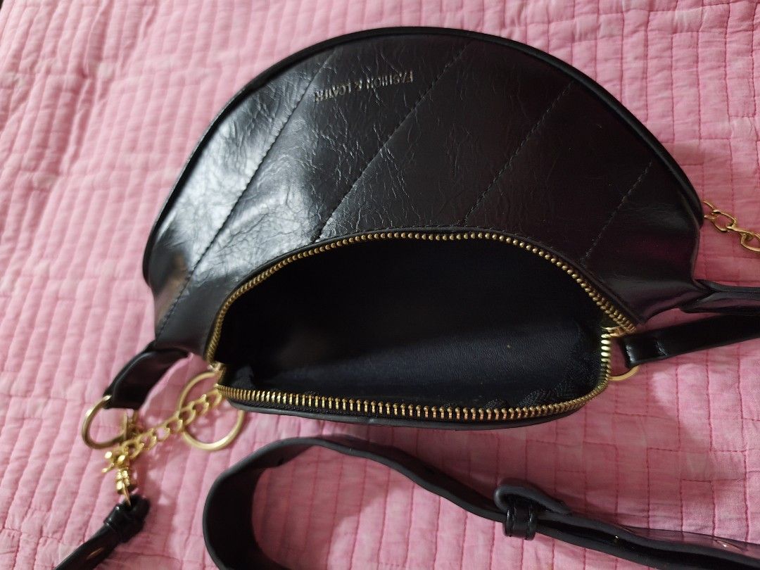 Black crescent shoulder bag with gold chain strap (Category: Cross-body Bags) located in Bulacan. Submitted by gelvy1316 (Listing ID 1466254948, Image 2). Description: - Style: Trendy half-moon shoulder bag in sleek black faux leather - Design: Elegant quilted diagonal stitching on the front with a stylish gold-tone chain accent - Closure & Interior: Secure top zipper opening to a clean, fully lined compartment - Straps & Hardware: Includes a rem