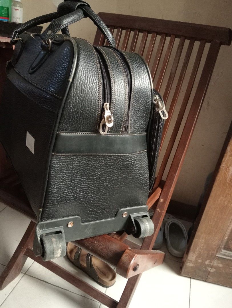 Black rolling duffel bag with wheels and handle (Category: Luggage) located in Makati City. Submitted by YSL80022 (Listing ID 1466275269, Image 3). Description: - Black textured material with structured shape. - Material: synthetic leather - Dual zipper main compartment plus front zip pocket - Top carrying handle and two wheels at the bottom base - Roomy interior for travel or overnight trips. - Sturdy construction, zippers work smoothly..