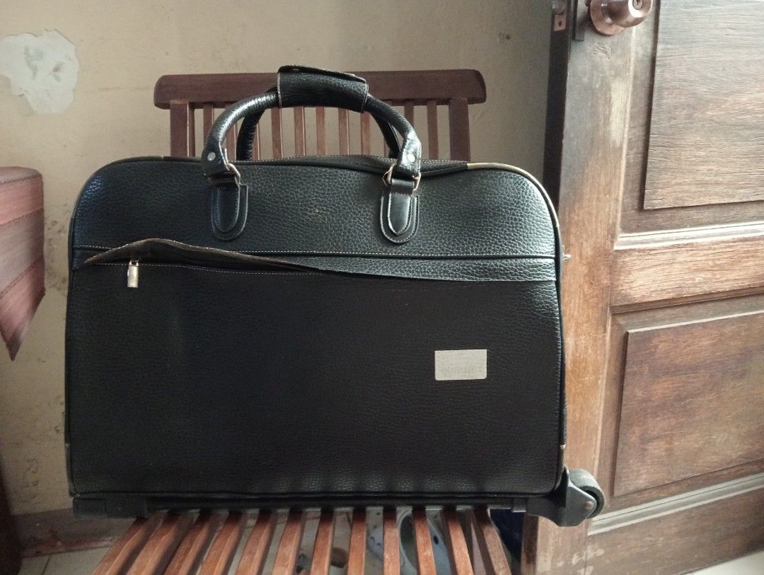 Black rolling duffel bag with wheels and handle (Category: Luggage) located in Makati City. Submitted by YSL80022 (Listing ID 1466275269, Image 2). Description: - Black textured material with structured shape. - Material: synthetic leather - Dual zipper main compartment plus front zip pocket - Top carrying handle and two wheels at the bottom base - Roomy interior for travel or overnight trips. - Sturdy construction, zippers work smoothly..