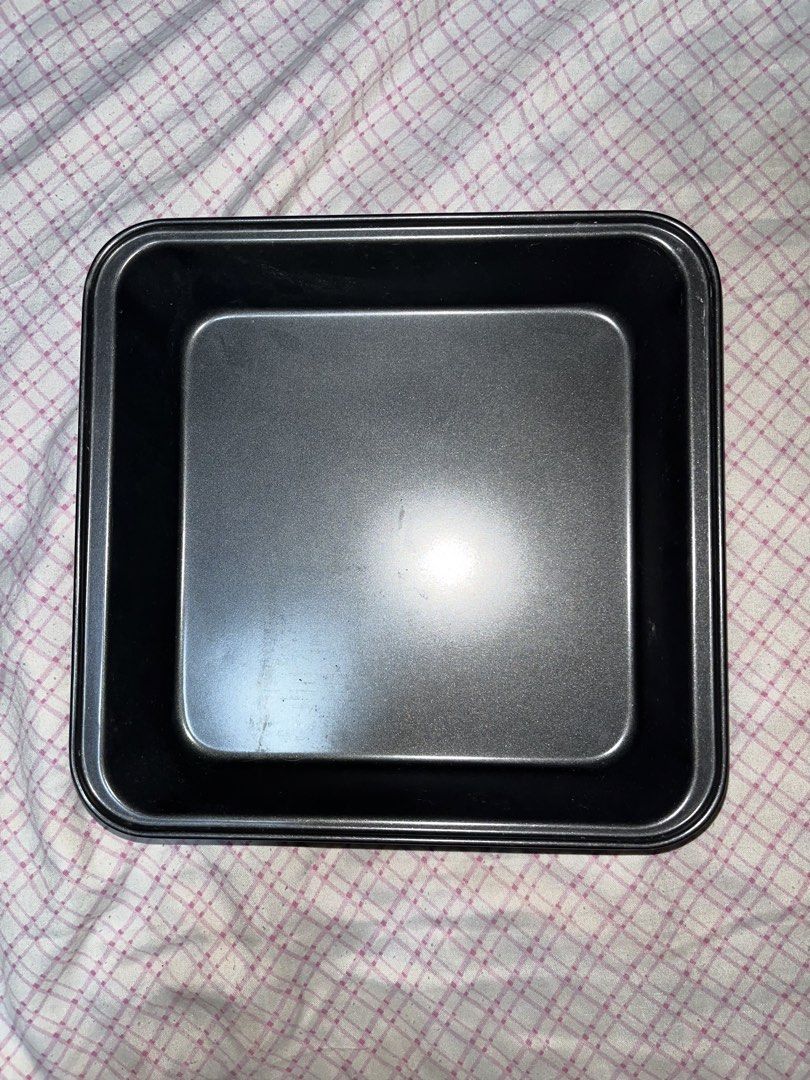 Black square baking pan non-stick metal cake tin (Category: Bakeware) located in Makati City. Submitted by kaiii.25 (Listing ID 1466205463, Image 1). Description: - Type: Square baking pan - Material: Dark metal with non-stick coating inside - Ideal for: Brownies, small cakes, and roasted vegetables - Condition: Clean surface with minor signs of handling on the bottom - Status: Ready for your next baking project.