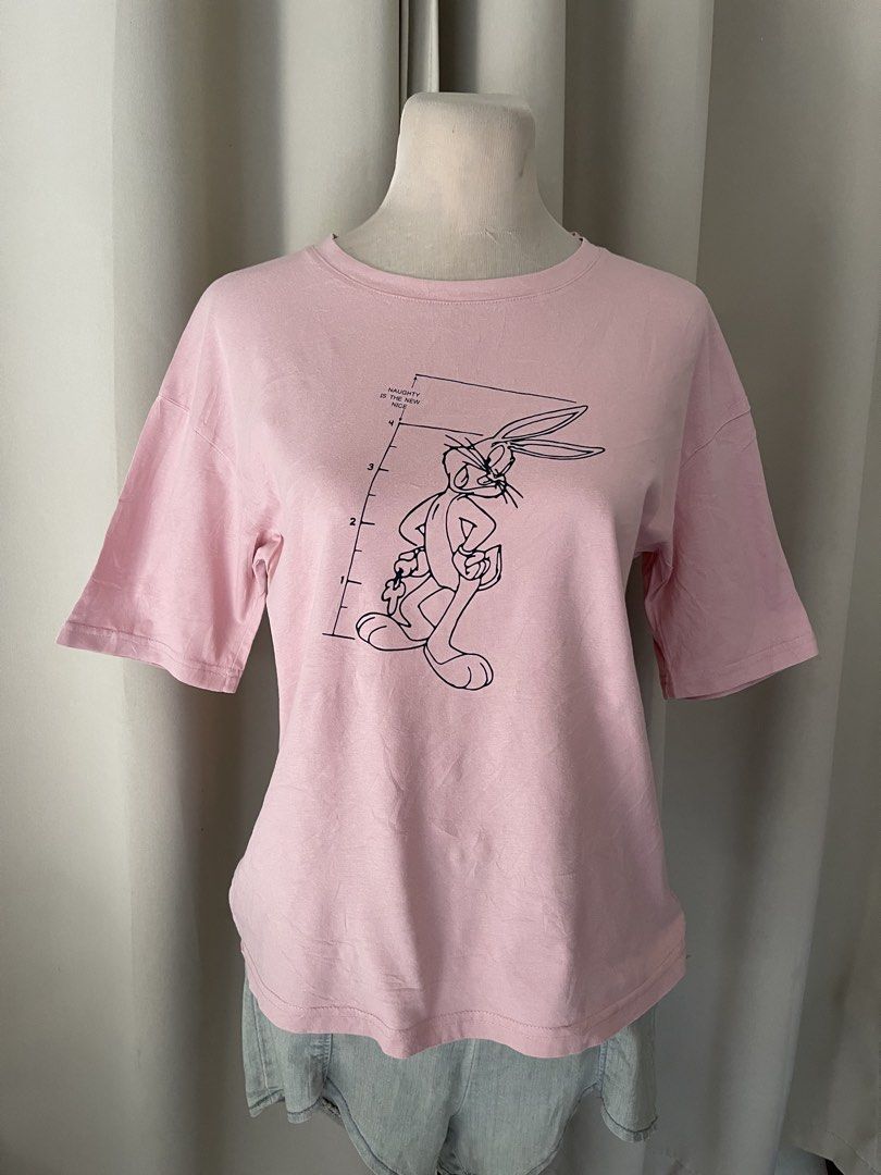 BUNDLE Elf Sack Looney Tunes Bugs Bunny (Category: Shirts) located in Cainta. Submitted by zlove111 (Listing ID 1466163591, Image 2). Description: - Brand: Elf Sack (Official Looney Tunes 70 each 2 for 110 small on tag can fit up to large boxy style cottom no issue merchandise with WBEI s20 tag) - Design: Bugs Bunny police lineup height chart with 'Naughty is the new nice' text - Color: Pink - Fit: Relaxed fit, classic crew neck, short sleeves - 
