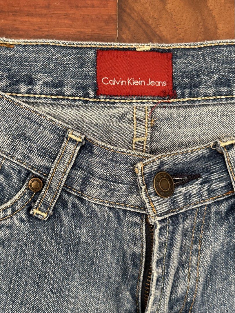 Calvin Klein Jeans Light Wash Denim (Category: Jeans) located in Cainta. Submitted by buy.preloved (Listing ID 1466192517, Image 2). Description: - Brand: Calvin Klein - Size W 29 - Wash: Light wash denim - Cut: Classic straight or slightly flared leg - Style: Vintage 90s aesthetic - Details: Distressed accents near right front and back pockets - Hardware: Zip fly with durable brass hardware - Special Features: Branded buttons and unique red inte