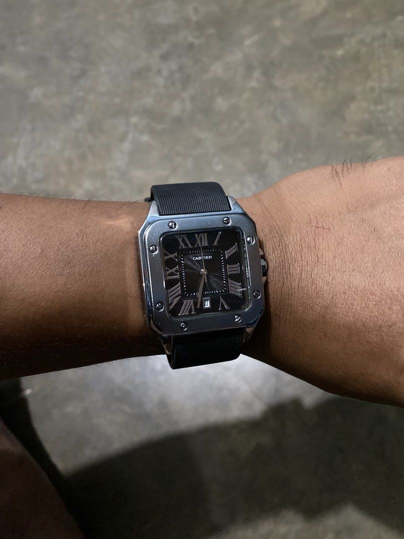 Cartier Santos 100 Black Dial Rubber Strap Watch (Category: Luxury Watches) located in Abulug. Submitted by axeldot (Listing ID 1466249528, Image 3). Description: - Authentic Cartier Santos 100 timepiece - Bold black textured dial with classic Roman numerals - Silver-tone square case with signature exposed screws - Practical date window at the bottom - Comfortable black ribbed rubber strap with standard pin buckle - Automatic movement and engrave