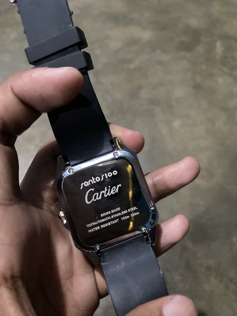 Cartier Santos 100 Black Dial Rubber Strap Watch (Category: Luxury Watches) located in Abulug. Submitted by axeldot (Listing ID 1466249528, Image 2). Description: - Authentic Cartier Santos 100 timepiece - Bold black textured dial with classic Roman numerals - Silver-tone square case with signature exposed screws - Practical date window at the bottom - Comfortable black ribbed rubber strap with standard pin buckle - Automatic movement and engrave